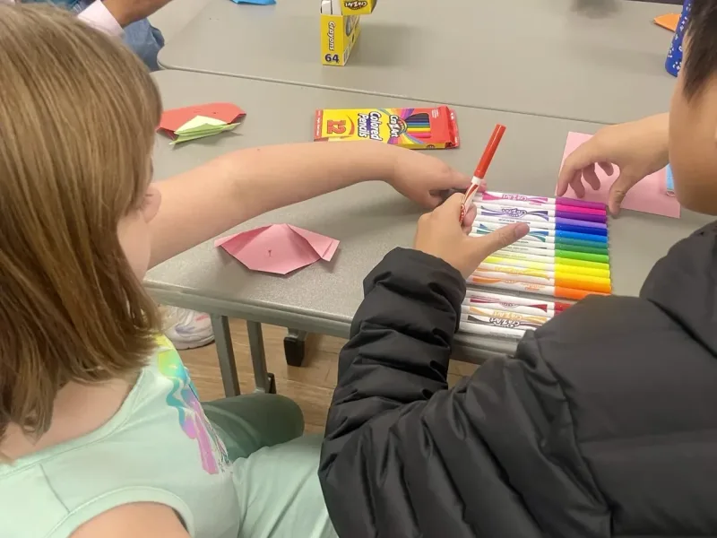Volunteer helping a student with an art project